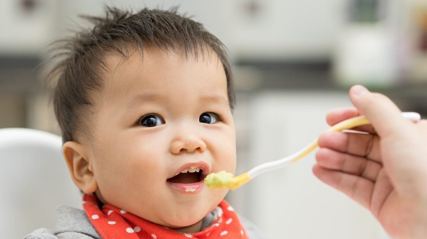 Asian baby boy eating blend food on a high chair